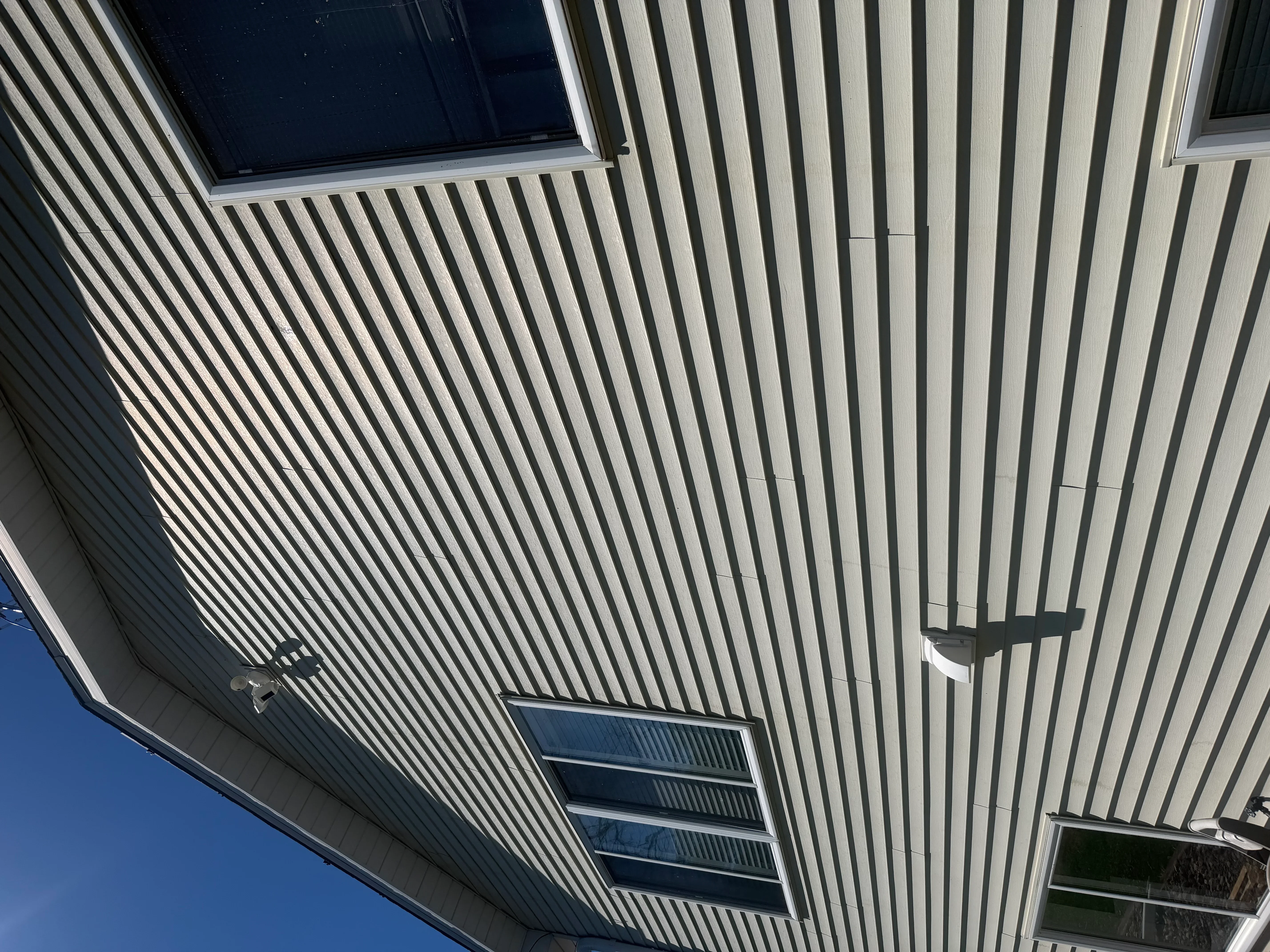Clean white corrugated metal siding with windows and ventilation louvers on commercial building