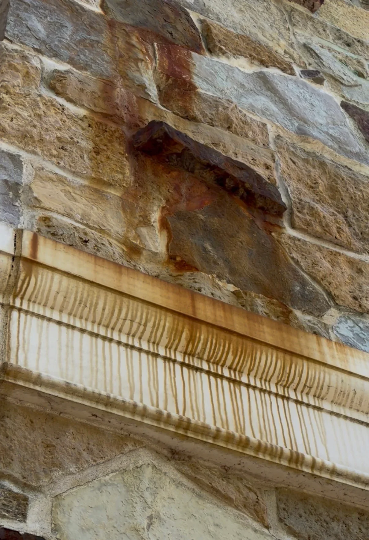 Cleaned stone masonry wall with wood soffit trim, rust stains removed