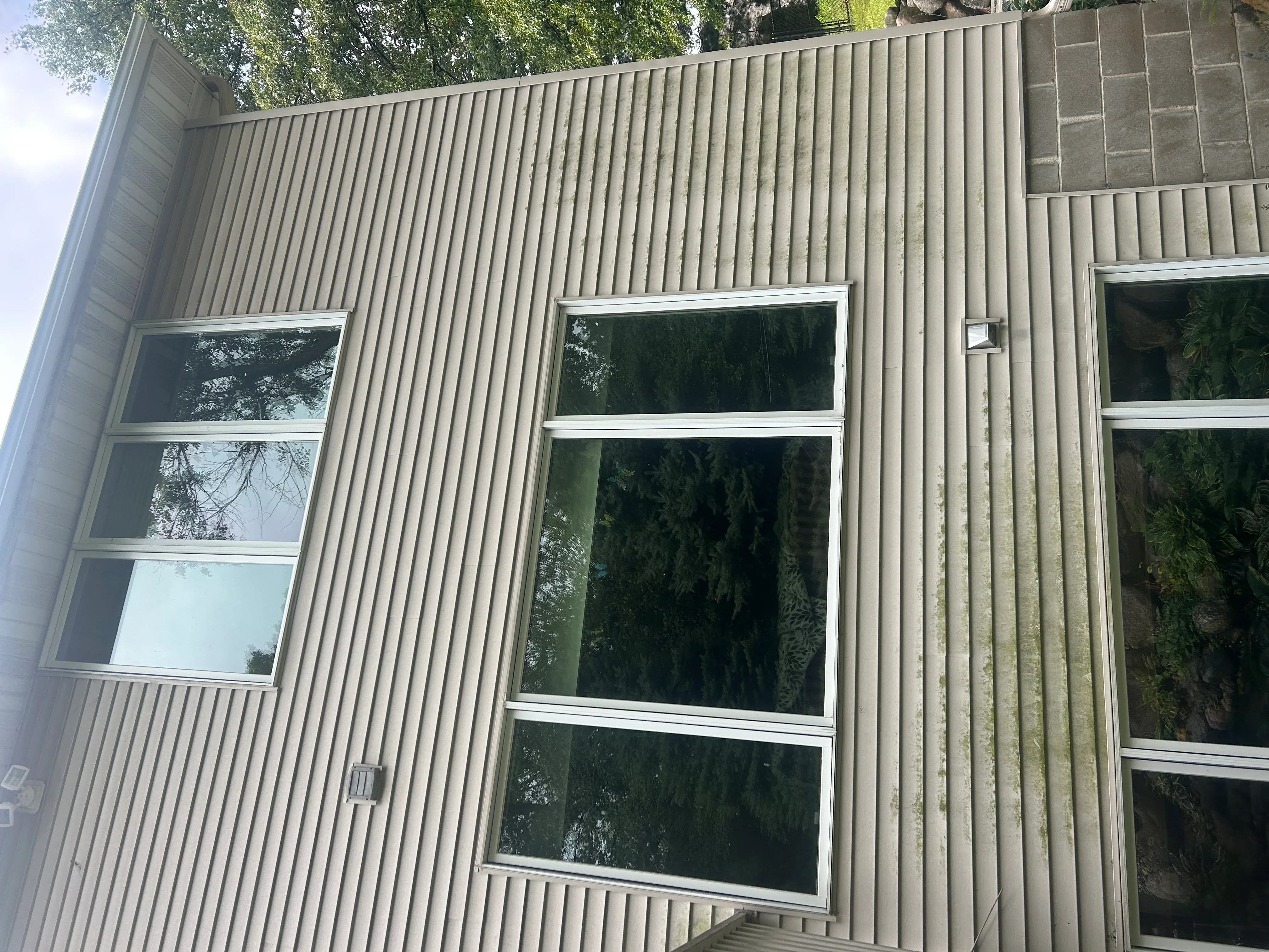 Clean corrugated metal building facade with three large windows featuring white frames and trim